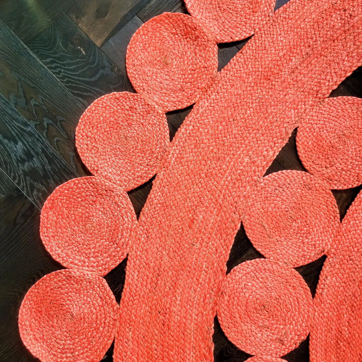 Close-up view of the Maia Classic Circles Round Jute Rug in red, showcasing its intricate braided design and circular patterns, perfect for enhancing large living room spaces. This living room area rug adds a vibrant touch to any decor with its natural jute texture.