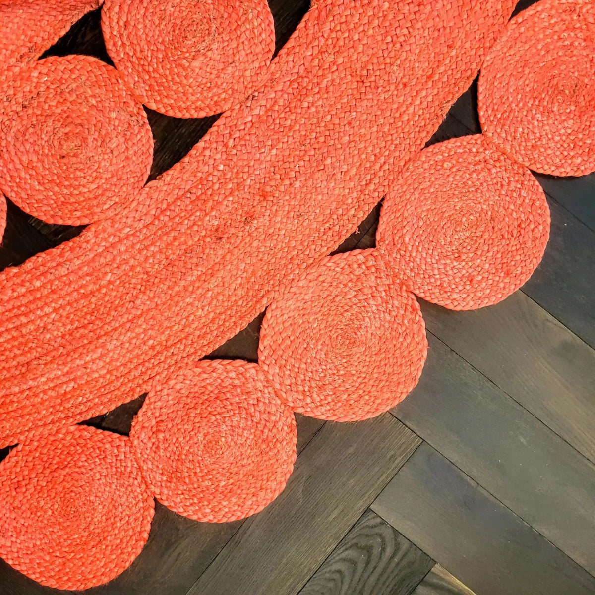 Close-up view of the Maia Classic Circles Round Jute Rug in vibrant red, showcasing its intricate woven pattern. This large area rug, perfect for a living room, features circular designs that add a touch of elegance and warmth to any space.