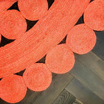 Close-up view of the Maia Classic Circles Round Jute Rug in vibrant red, showcasing its intricate woven pattern. This large area rug, perfect for a living room, features circular designs that add a touch of elegance and warmth to any space.
