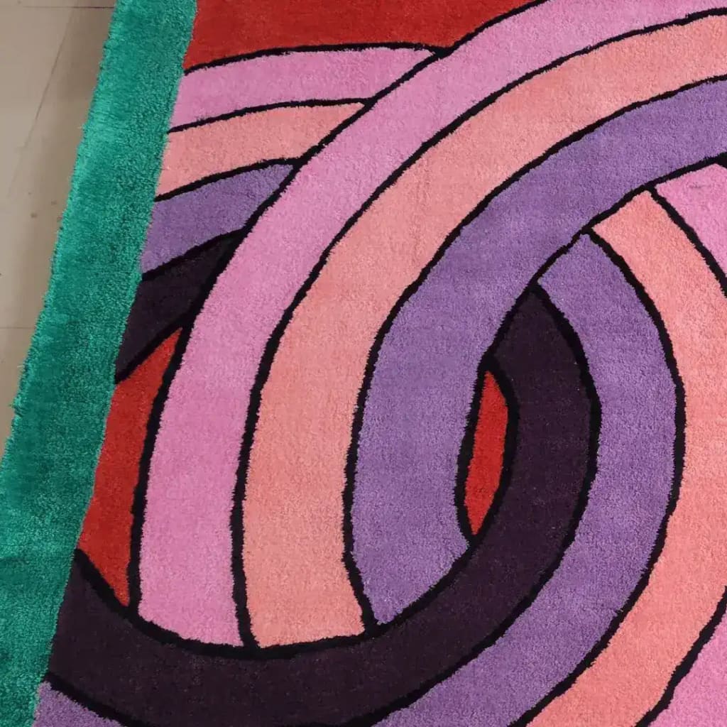 Close-up view of the Maia Knotted Circles on Square Hand Tufted Wool Rug in green, featuring bold, overlapping circular patterns in vibrant pink, purple, and red tones. This contemporary square area rug adds a modern touch to living rooms or offices, showcasing its plush wool texture.