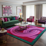 Modern living room with a colorful rug, green sofa, and abstract art on the walls.