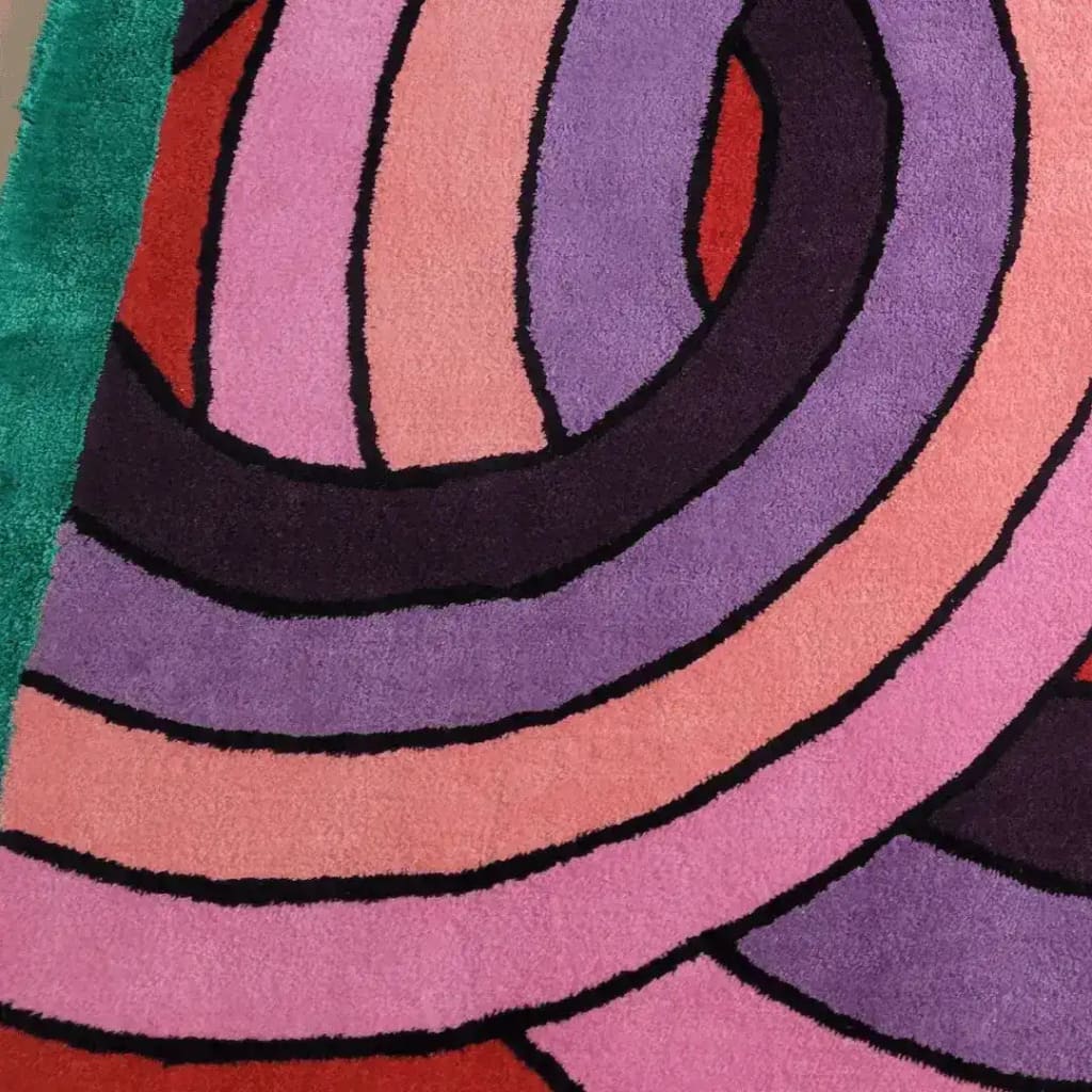 Close-up view of a contemporary wool area rug featuring vibrant, knotted circles in shades of pink, purple, and red on a green background. Perfect for adding a modern touch to living rooms or offices, this square rug offers a stylish and bold design.