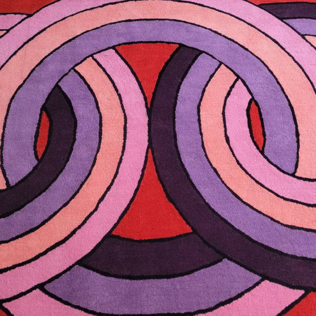 This vibrant square area rug features an intricate pattern of interlocking circles in shades of purple, pink, and red. The contemporary design is perfect for adding a pop of color to a living room or office space. Made from high-quality wool, this hand-tufted rug offers both style and durability, making it an ideal choice for those seeking unique and artistic living room area rugs or rugs for office spaces.