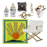 A vibrant contemporary wool rug featuring an art deco design with a sunburst pattern in orange, yellow, and green tones. This square area rug is displayed in a living room setting alongside decorative vases, a checkered cushion, a modern chair, and artistic accents, creating a stylish and inviting space. Ideal for those seeking large living room rugs with a modern flair.