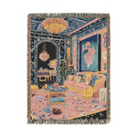 Portrait fringed woven throw showing opulent room with chandelier floral walls pink sofa and patterned carpet in navy and pink on the Maximalist Dreamscape Woven Blanket