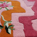 Close-up of a colorful textured rug with pink and orange patterns.
