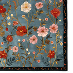 The Meadow Muse Hand Tufted Rug showcases a beautiful floral pattern in vibrant reds, pinks, and yellows on a soft blue background. This elegant area rug, made from wool, is perfect for adding a vintage touch to living rooms. Ideal as an area rug for living room spaces, it combines style and comfort seamlessly.