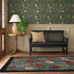 This inviting area rug, the Meadow Muse Hand Tufted Rug, showcases a vibrant floral design with red and pink blossoms against a blue background, perfect for adding a touch of elegance to your living room. Crafted from high-quality wool, this vintage rug enhances any space, making it an ideal choice for those seeking stylish rugs for living room decor.