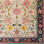 A beautifully crafted Medallion Bloom Hand Knotted Area Rug featuring a vibrant floral design. The rug displays intricate pink, yellow, and blue flowers with green foliage on a cream background, bordered by a richly detailed navy edge. This vintage rug brings a touch of elegance to large living room spaces, resembling traditional Persian rugs.