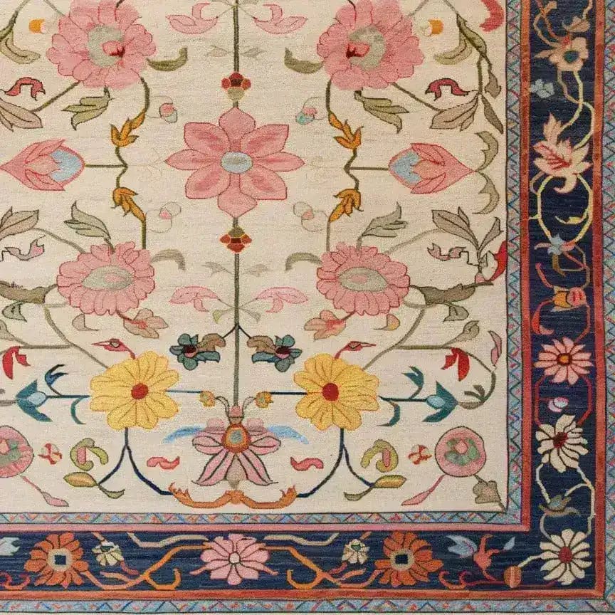 A beautifully crafted Medallion Bloom Hand Knotted Area Rug featuring a vibrant floral design. The rug displays intricate pink, yellow, and blue flowers with green foliage on a cream background, bordered by a richly detailed navy edge. This vintage rug brings a touch of elegance to large living room spaces, resembling traditional Persian rugs.