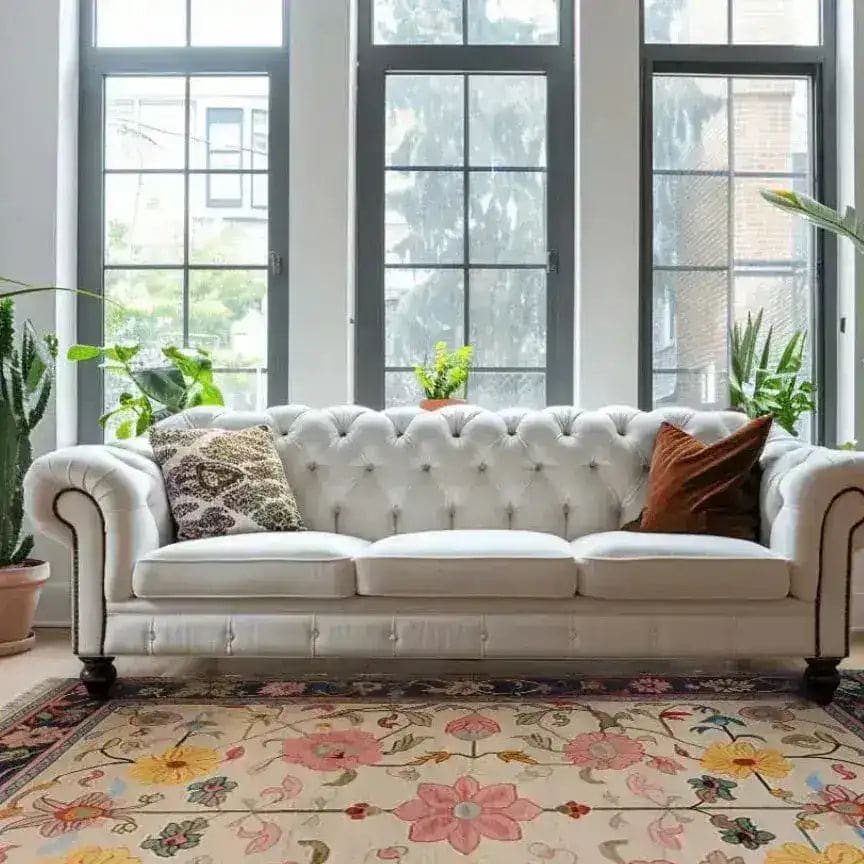 A beautifully styled living room features a Medallion Bloom Hand Knotted Area Rug with floral patterns, complementing a white tufted sofa. Perfect for large living room spaces, this vintage Persian rug adds elegance and charm.