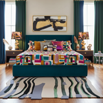 Colorful geometric-patterned bedspread on a teal bed in a stylish bedroom with an abstract rug