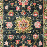 Close-up view of the Midnight Bloom Mosaic Hand Tufted Area Rug, showcasing its intricate floral design. This wool rug features a vibrant pattern with pink, red, and green flowers on a dark background, perfect for large living room spaces. A beautiful example of floral and area rugs for living room settings.