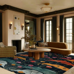 A beautifully styled living room featuring the Midnight Garden Hand Tufted Area Rug. This contemporary floral rug adds a vibrant touch with its colorful floral design on a dark background, perfectly complementing the modern furniture and large windows. Ideal for those seeking large living room rugs with a vintage flair. This wool rug enhances the cozy yet elegant atmosphere in the living room.