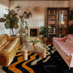 A stylish living room featuring a Midnight Mirage Tufted Wool Rug. This contemporary area rug showcases an abstract design in rich colors, perfectly complementing the plush velvet sofas and glass coffee table. Ideal for anyone seeking large area rugs for a modern living room.