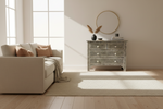 Midnight monochrome bone inlay 4 drawers chest in a bright room with a cream sofa and round mirror.