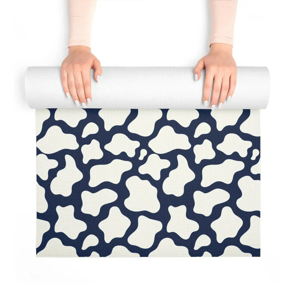 Hands unrolling the navy and cream mosaic yoga mat, textured non-slip surface visible