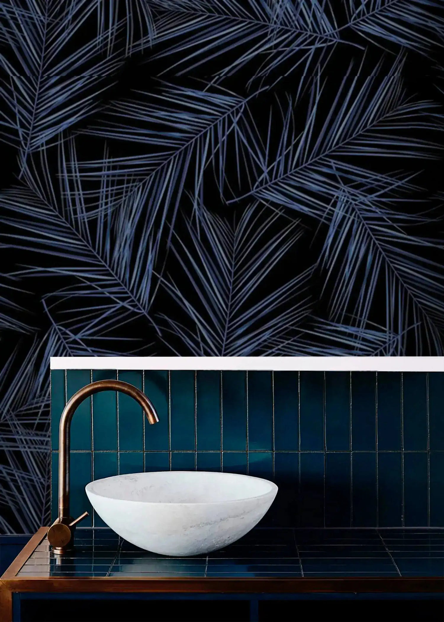 Midnight Oasis dark navy wallpaper with blue tropical palm fronds in bathroom; marble vessel sink and brass faucet