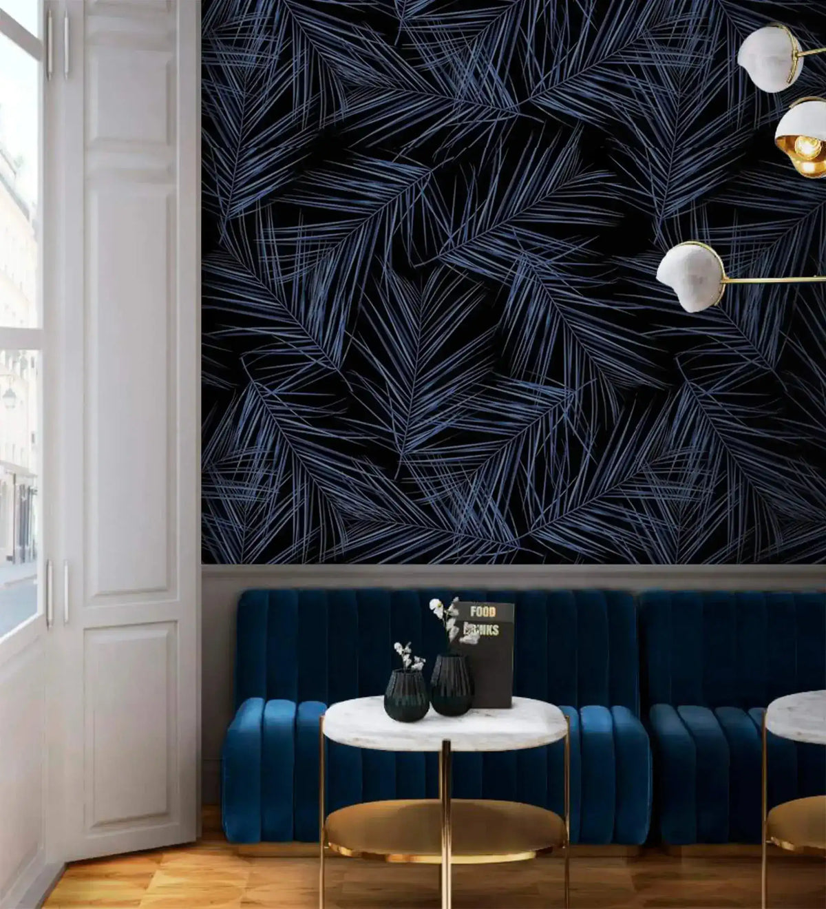 Midnight Oasis blue-black tropical leaf wallpaper in lounge; navy velvet banquette, gold marble side tables, globe pendants