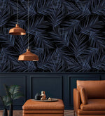 Midnight Oasis dark navy tropical palm wallpaper above navy wainscoting; copper pendants, tan leather chair and ottoman