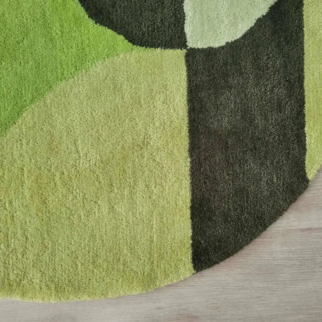 Close-up view of the Mini Maia Geometric Round Hand Tufted Wool Rug, showcasing its vibrant green and black geometric design. Perfect as a large living room rug, this round wool rug adds a modern touch to any living room or office space.