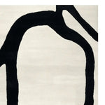 A contemporary area rug featuring a minimalist hand-tufted design with bold black abstract lines on a soft white wool background, perfect for modern living rooms.