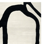 A contemporary area rug featuring a minimalist hand-tufted design with bold black abstract lines on a soft white wool background, perfect for modern living rooms.
