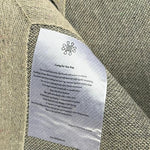 Close-up view of the Mocha Mirage Hand-Tufted Rug, showcasing the intricate weave and care instructions tag. This contemporary wool rug is perfect for adding elegance to your dining room, serving as a stylish large area rug that complements any formal dining room setting.