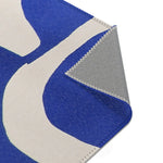 Modern Abstract Blue & White Rug bottom-right corner fold — arching abstract shapes with grey backing and overlock stitch at corner
