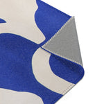Modern Abstract Blue & White Rug upper-right corner fold — abstract blue shapes at pile edge, backing detail with overlock stitch