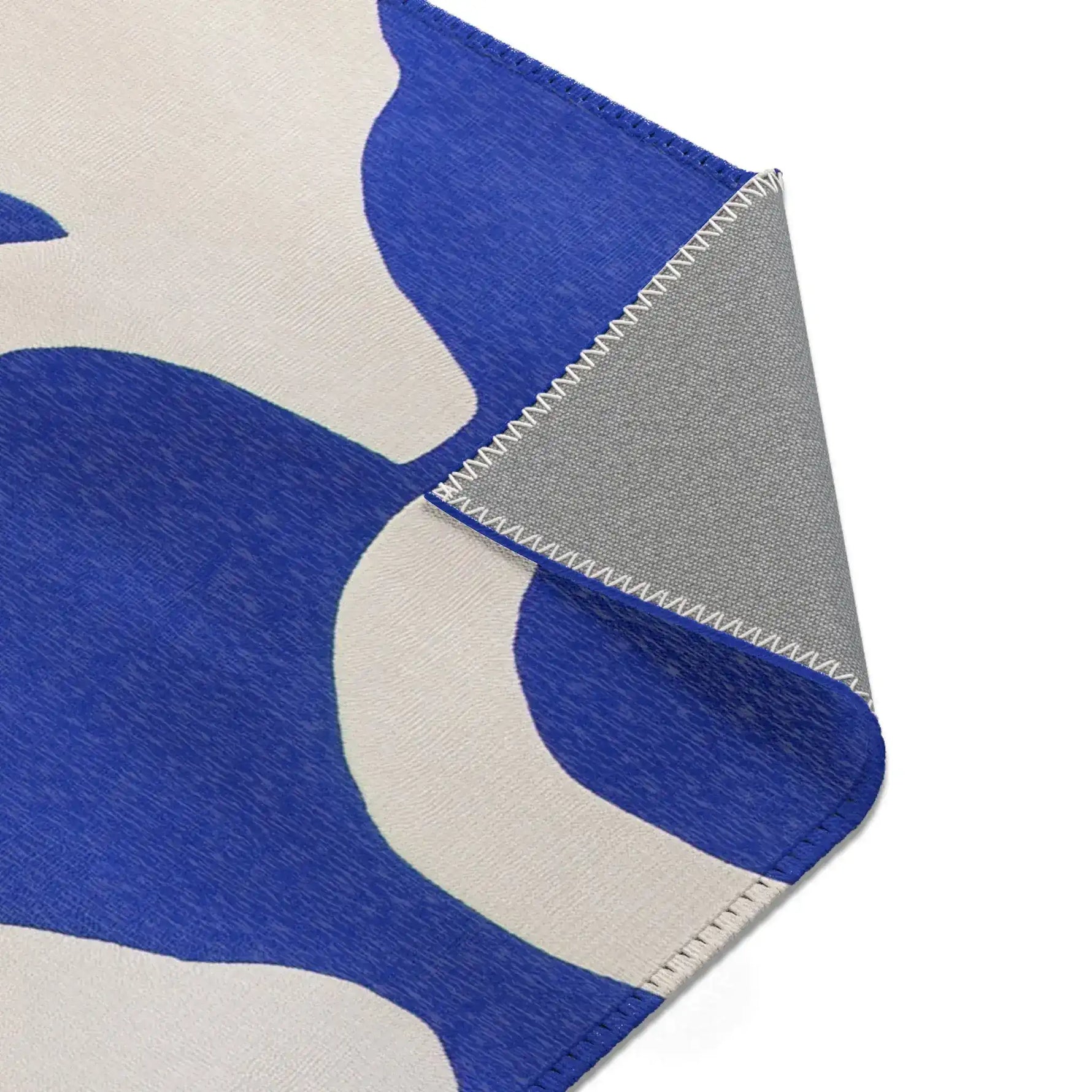 Modern Abstract Blue & White Rug upper-right corner fold — abstract blue shapes at pile edge, backing detail with overlock stitch
