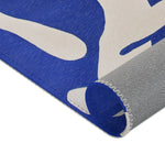 Modern Abstract Blue & White Rug rolled corner close-up — navy pile curling back to reveal cream face backing and grey underside edge