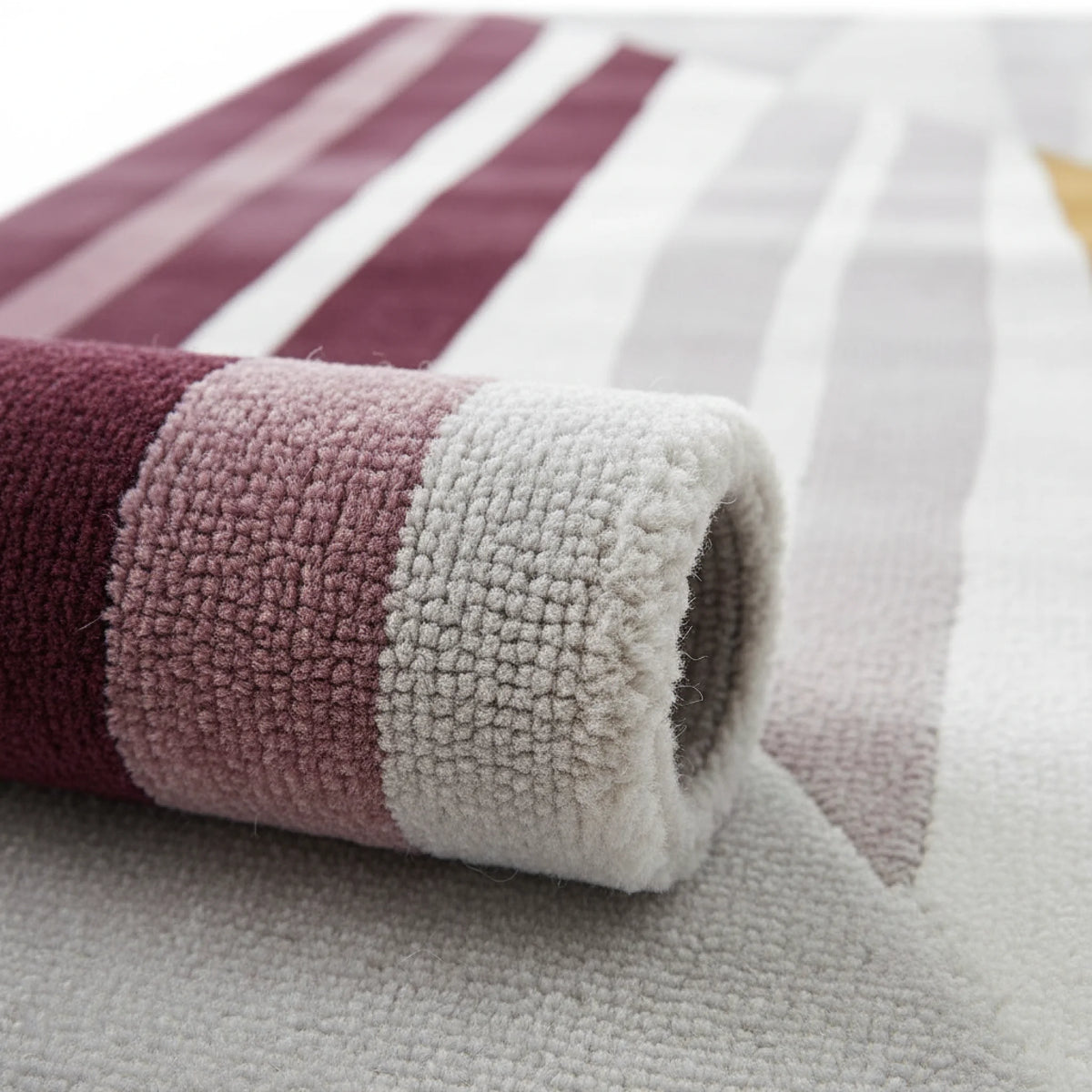 Close-up of a striped tufted wool rug with purple, pink, and white colors.