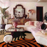Living room with a patterned geometric vibrant wool rug, white sofa, and decorative mirror.