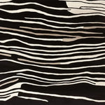 A striking area rug with a black and white abstract pattern, part of the Modular Art Beat collection. This contemporary wool rug, designed for living room spaces, showcases a hand-tufted texture with flowing lines that resemble natural forms.