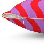 Close-up view of a vibrant throw pillow featuring a pop-inspired design with red and purple waves, showcasing a zipper detail.