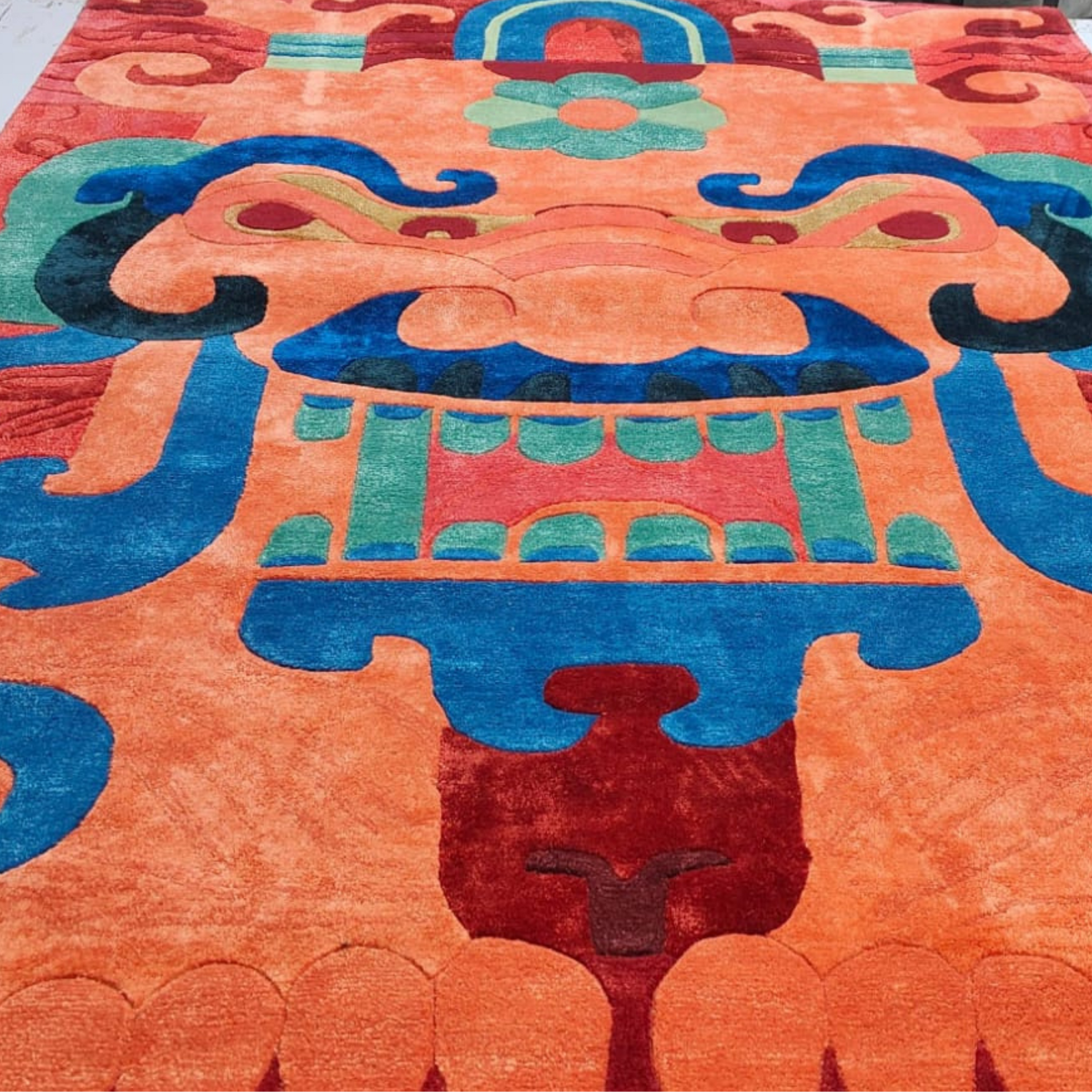 Colorful patterned tufted wool rug with intricate design on an orange background