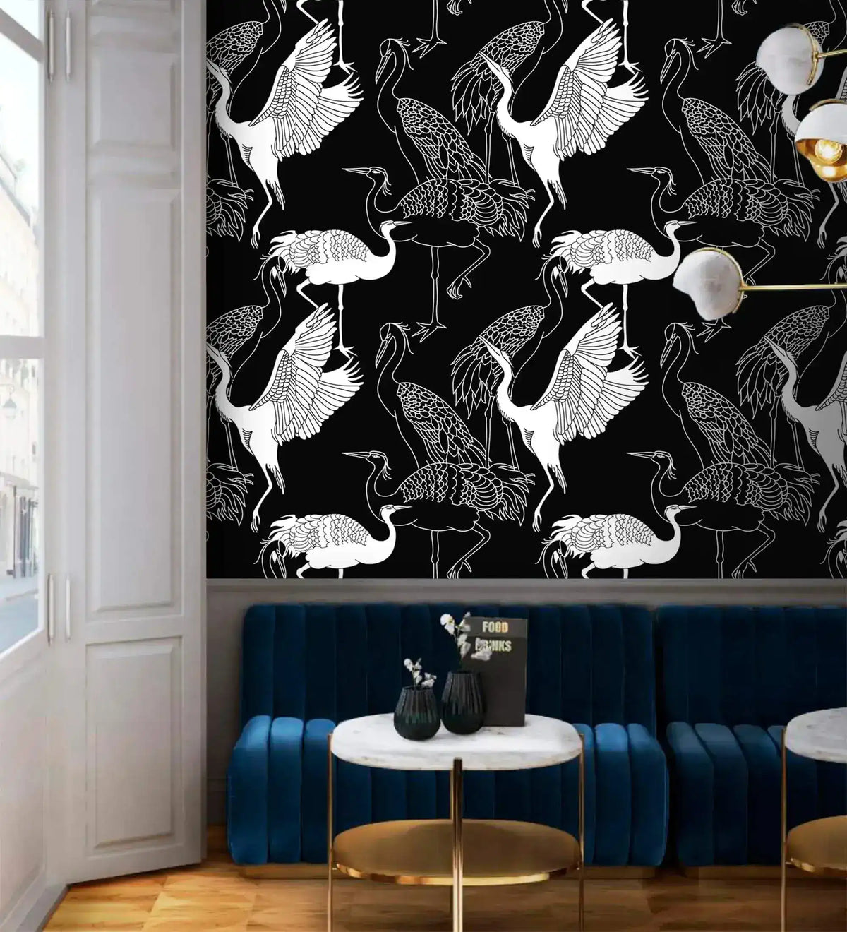 Monochrome crane wallpaper with white cranes on black above a navy velvet banquette and marble table