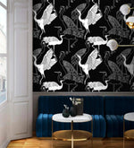 Monochrome crane wallpaper with white cranes on black above a navy velvet banquette and marble table