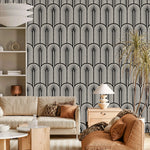 Monochrome Deco arch-and-frond wallpaper behind a cream boucle sofa and rust seating