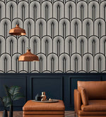 Monochrome Deco fan wallpaper above navy panelling with copper pendants and tan leather chair