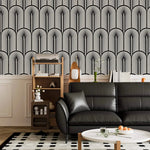 Monochrome Deco fan wallpaper above white panelling with a black leather sofa and ladder shelf