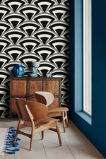 Monochrome deco fan wallpaper beside a blue wall with antique cabinet and curved wood chairs
