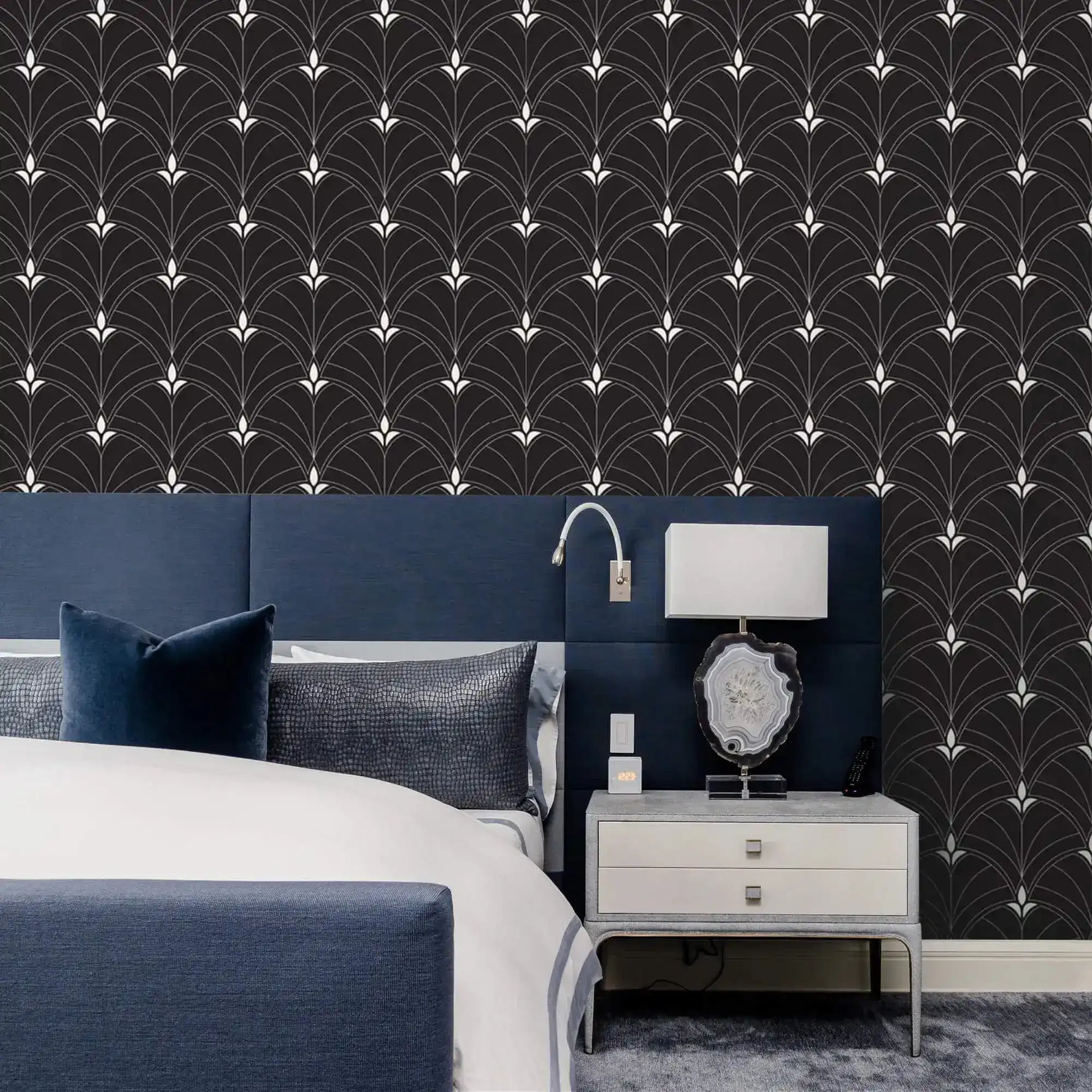 Black and white Art Deco arch wallpaper behind navy upholstered headboard, with agate-base lamp on silver bedside table