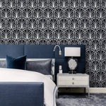 Monochrome vintage geometric wallpaper, white art deco palmette fans on navy behind an upholstered bed