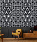 Monochrome vintage geometric wallpaper, white deco palmettes on black above paneling with yellow chair