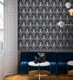 Monochrome vintage geometric wallpaper, white deco palmettes on navy above a blue velvet banquette