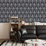 Monochrome vintage geometric wallpaper, white deco palmettes on navy above a black leather sofa