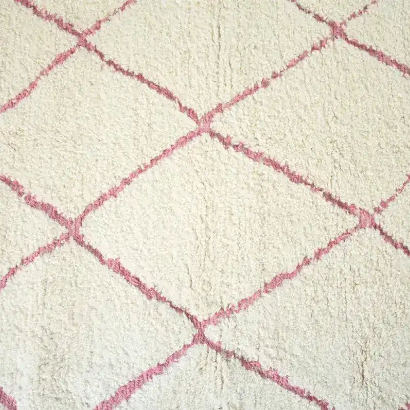 Close-up view of a Moroccan Pink Beni Ouarain Classic Area Rug, showcasing its plush wool texture and elegant pink diamond pattern. This large living room rug adds a touch of vintage charm to any space.