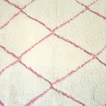 Close-up view of a Moroccan Pink Beni Ouarain Classic Area Rug, showcasing its plush wool texture and elegant pink diamond pattern. This large living room rug adds a touch of vintage charm to any space.